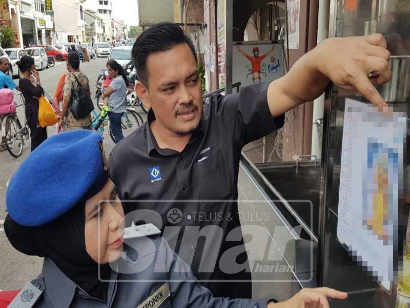 Mohd Ridzuan bersama timbalannya, Sapiah Mohd Noor menunjukkan tanda halal yang digunakan salah sebuah restoran makanan India yang diperiksa tadi.