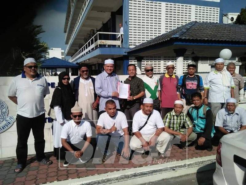 Khalil Idham Lim (tengah) menunjukkan laporan polis dibuat ke atas Peguam Negara mewakili NGO Gerakan Pembela Ummah Perak di perkarangan IPD Kuala Kangsar, hari ini.