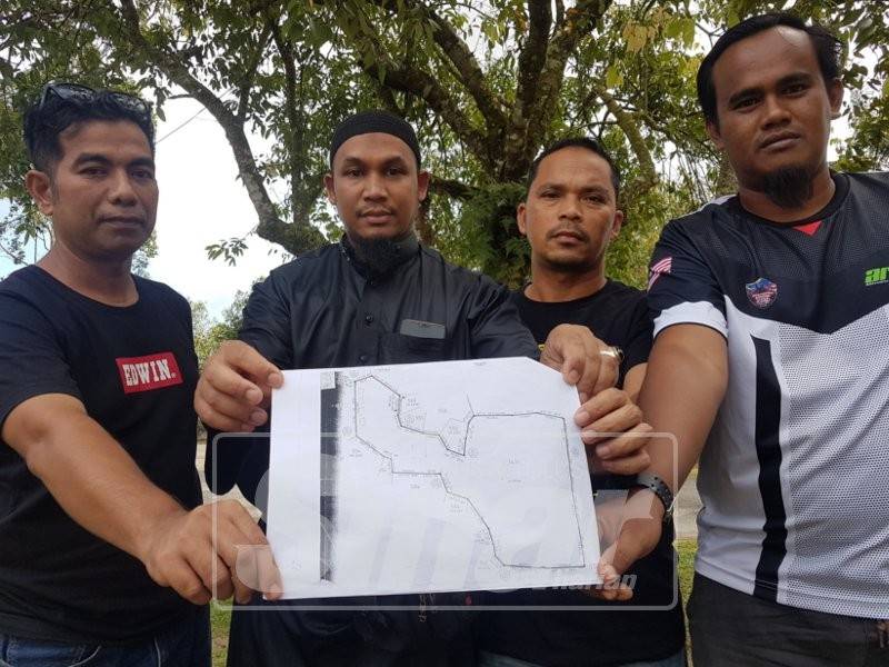 Rosli (kiri) bersama penduduk Kampung Payoh yang lain melihat pelan keluasan tanah di Kampung Bujal yang dipohon dijadikan RTB lot rumah.