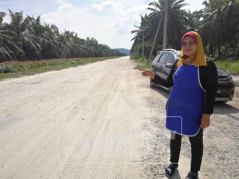 Latiffah menunjukkan jalan yang masih mendap dan berhabuk di hadapan kedai makannya.