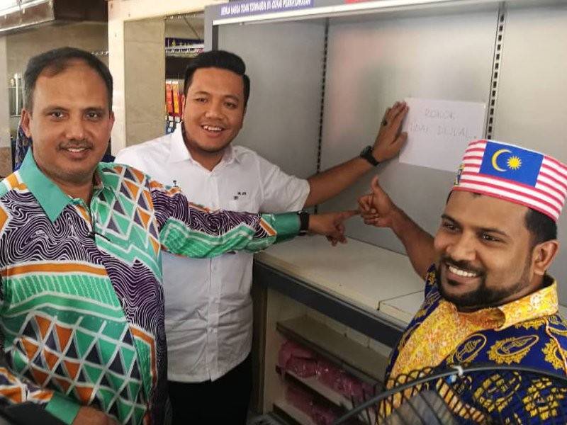 Dr Afif (dua,kanan) melekatkan poster 'Rokok Tidak Dijual Disini' di kaunter bayaran Restoran Nasi Kandar Pelita.