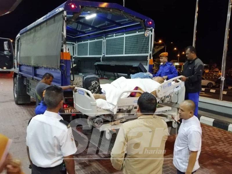 Norazman diangkat ke trak menggunakan katil beroda di Hospital Kuala Krai.