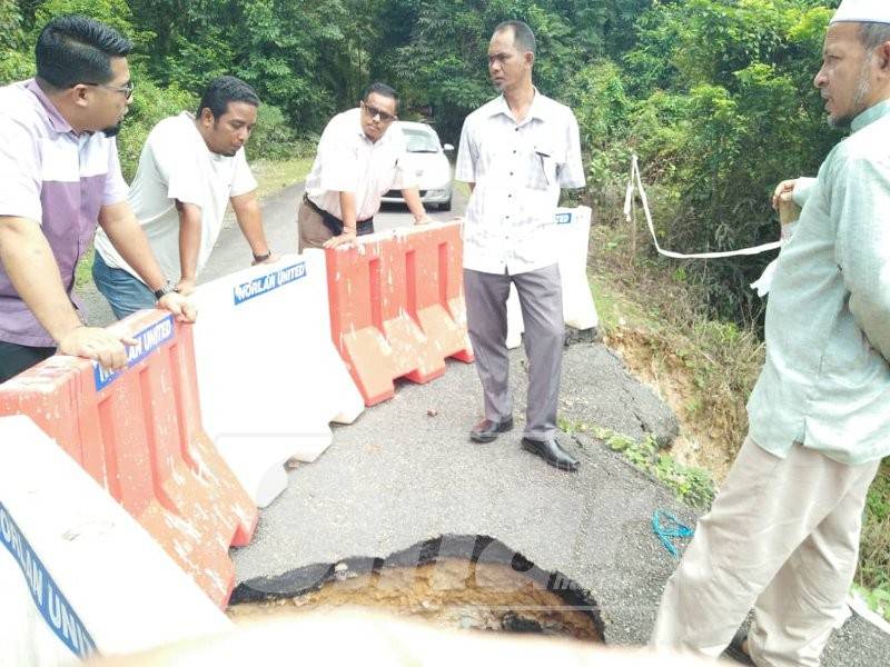 Ghazali (kanan) ketika meninjau keadaan jalan yang rosak dan berlubang.