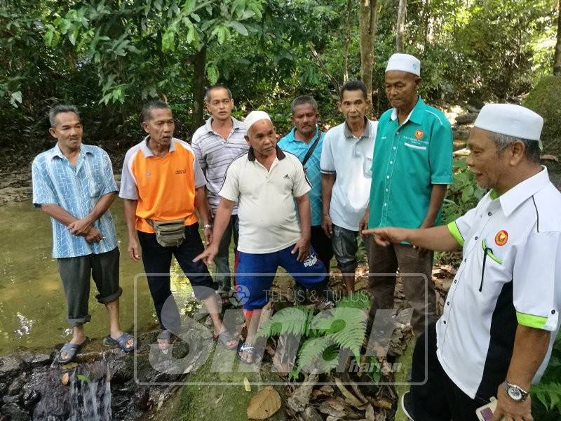 Abd Nasir (kanan) meninjau kolam tadahan air bersama penduduk.