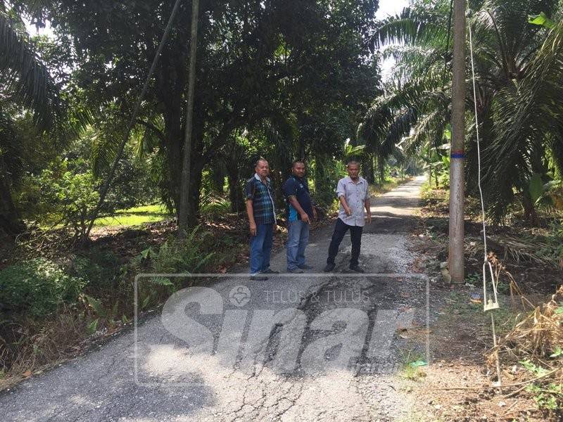 Zakaria (kanan) dan Ashaari (kiri) menujukkan jalan kampung rosak yang tidak dibaiki berikutan tiada ketua kampung untuk melaporkannya.