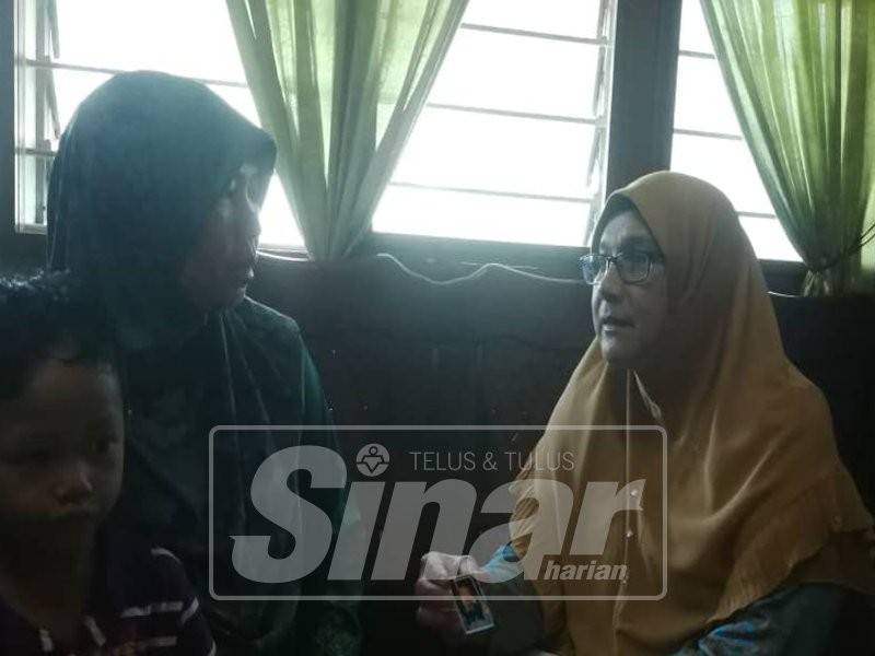 Dr Siti Mariah memegang gambar Allahyarham Eddie Erwan Marzuki ketika kunjungannya di Tanjong Karang.
