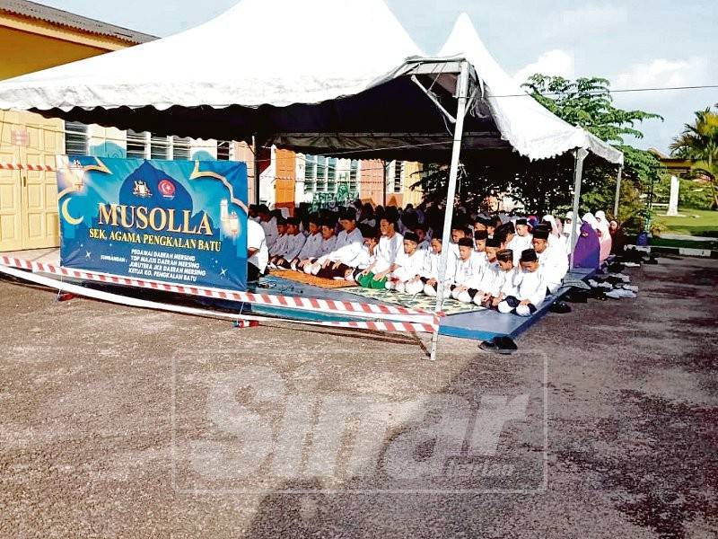 Pelajar Sekolah Agama Pengkalan Batu menunaikan solat berjemaah di bawah khemah.