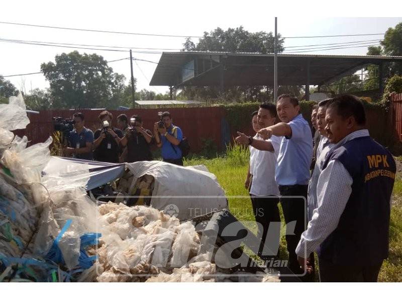 Sze Han (dua, kiri) menunjukkan sisa plastik yang ditemui semasa operasi bersepadu kilang plastik haram di sekitar Teluk Gong, hari ini.