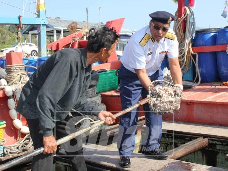 Rozali (kanan) menunjukkan anak-anak ikan yang ditangkap oleh dua bot nelayan tempatan kelas C menggunakan pukat tunda pada jarak lebih kurang 8.8 dan 8.9 batu nautika dari barat Tanjung Belua, Pulau Langkawi.