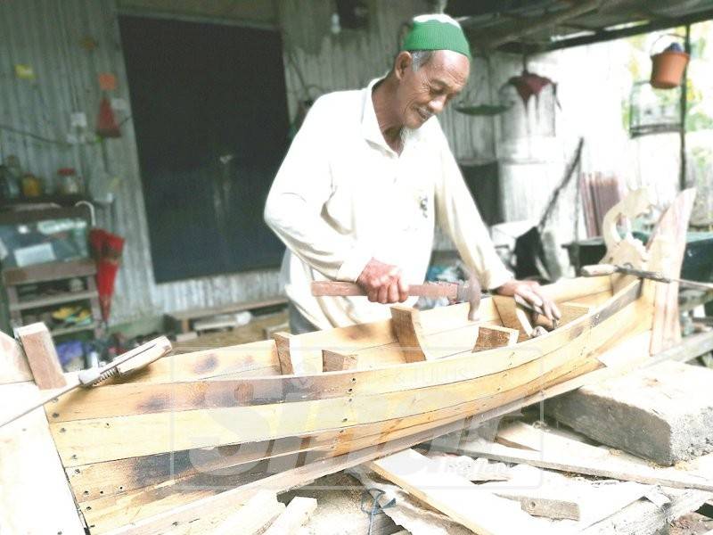 Ibrahim tekun menyiapkan replika perahu yang dimulakan sejak tiga minggu lalu.
