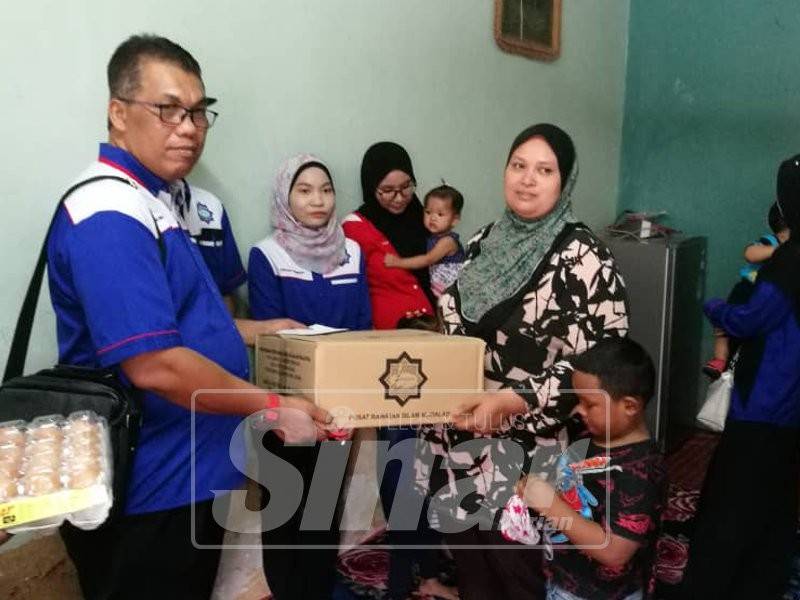 Baharudin menyampaikan sumbangan kepada seorang daripada tujuh penerima ketika Jelajah Sentuhan Kasih Ziarah Al Qalam di sekitar Puchong.