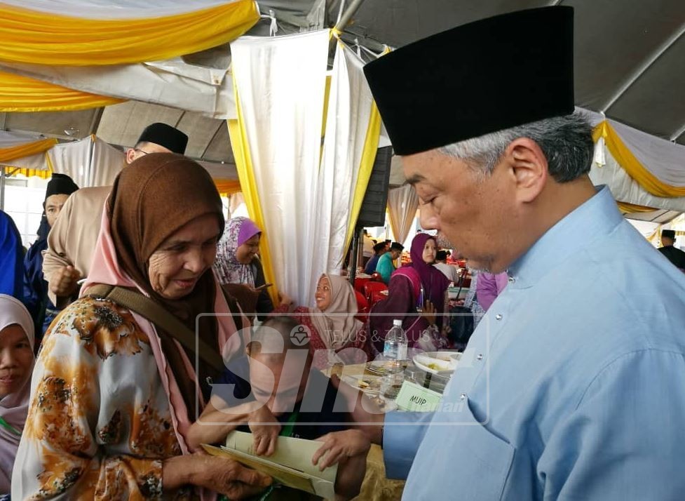 Al Sultan Abdullah (kanan) beramah mesra bersama penerima sumbangan, Rizal Rashid, 40 yang merupakan Orang Kurang Upaya (OKU) di Masjid Baharu Kuantan di sini, hari ini.