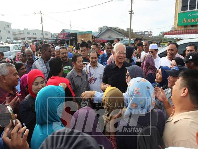 Kehadiran Najib di Pasar Tani Tapah disambut orang ramai yang mahu bersalaman dan mengambil gambar dengan beliau.