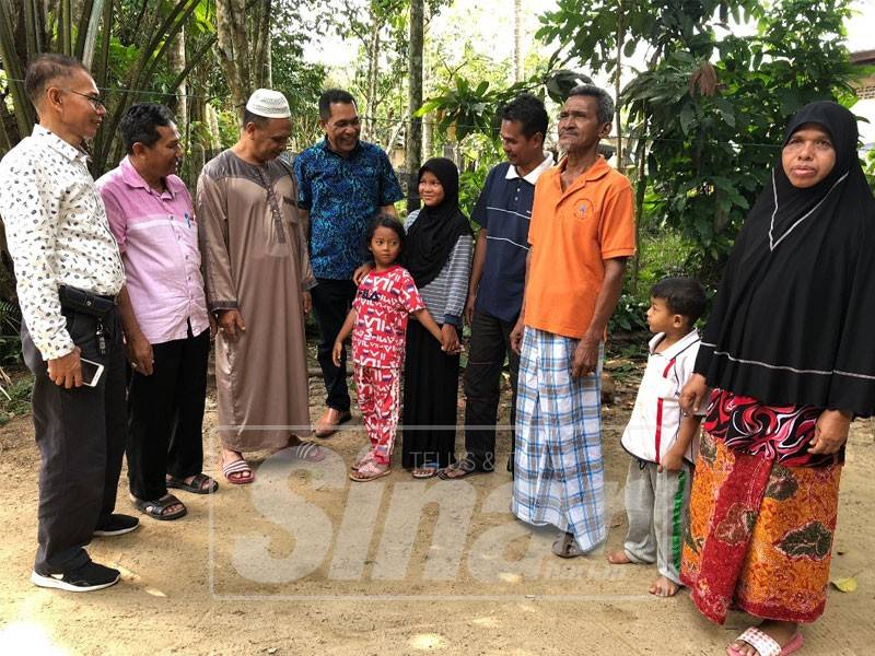 Arnawi (kiri) meninjau keadaan dua beradik di Kampung Batu Besar, semalam.