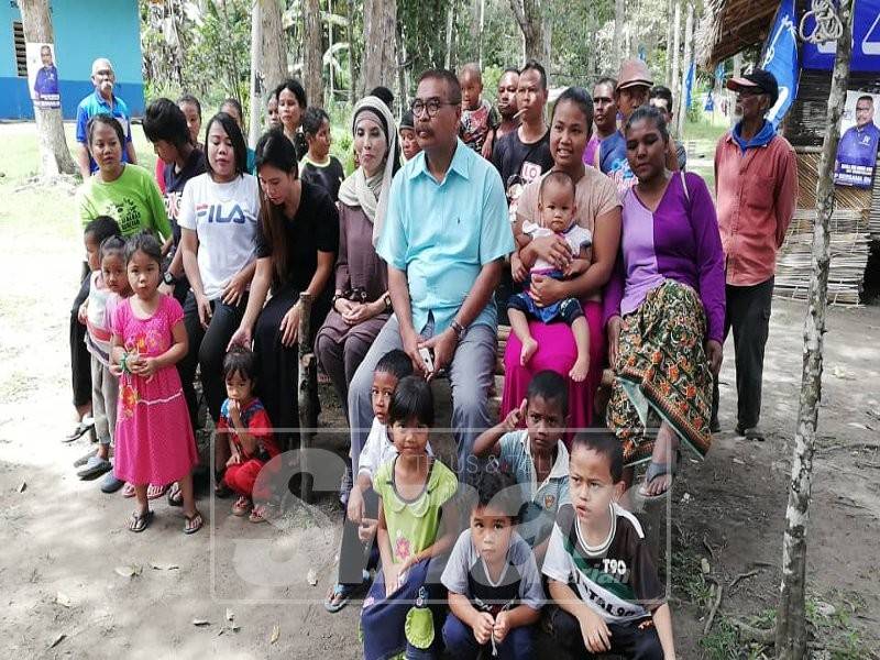 Ramli meluangkan masa dengan penduduk kampung Orang Asli Pos Menson, semalam.
