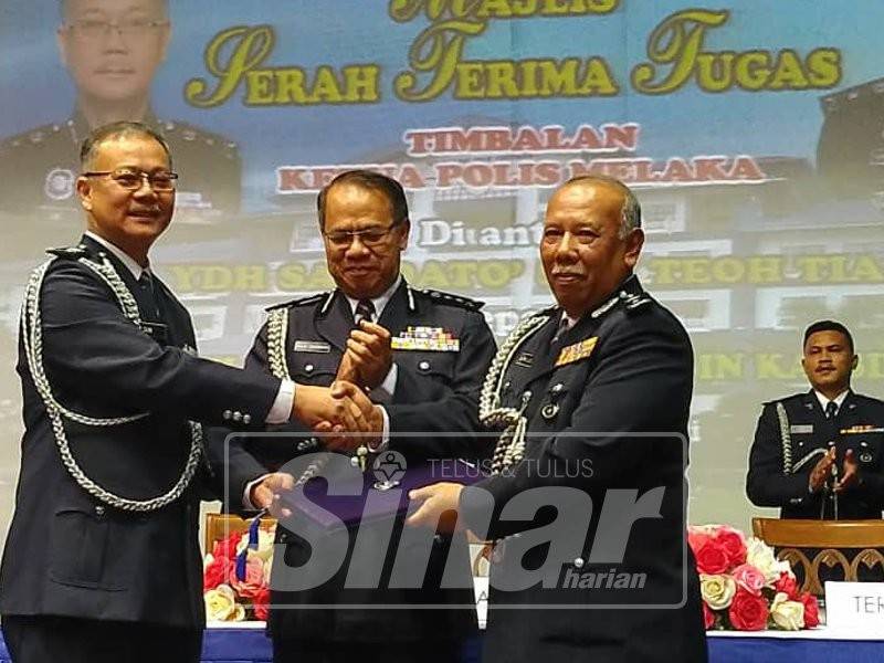 Teoh Tia (kiri) ketika menyerahkan tugas kepada Kamaluddin (kanan) disaksikan Raja Shahrom pada majlis serah tugas di IPK Melaka, Bukit Beruang, hari ini.