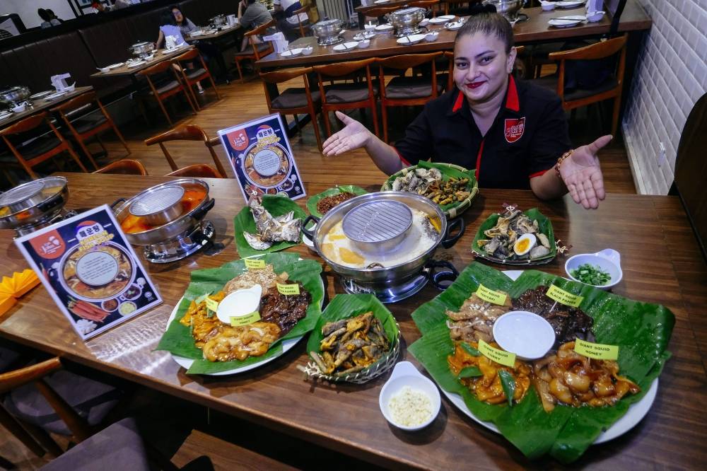 
Salah seorang pekerja Pak John Steamboat & BBQ menunjukkan antara menu yang ditawarkan.