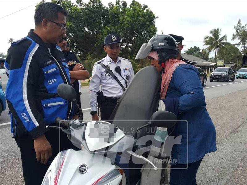 Abd Razak (kiri) memaklumkan tentang Ops Selamat sempena sambutan Tahun Baharu Cina kepada seorang penunggang motosikal di Kelulut, hari ini.