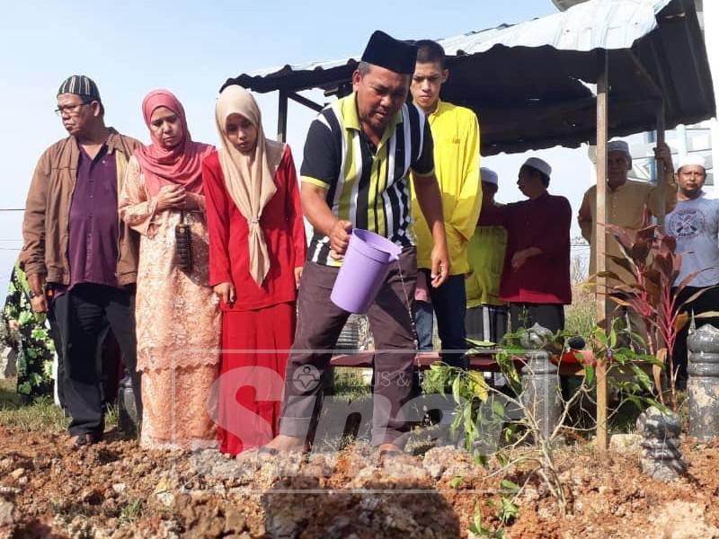 Abd Hamid menyiram air ke pusara anaknya selepas tamat bacaan talqin di Masjid An-Najah, Ayer Hitam. Turut kelihatan Zaiton (dua, kiri)