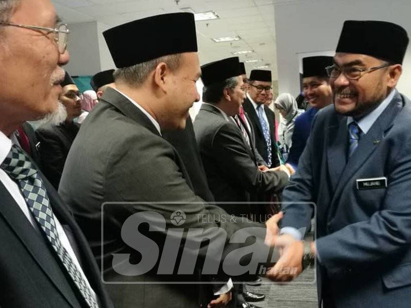 Mujahid bersalaman dengan Ahli Lembaga Pemegang Amanah selepas majlis Penyerahan Watikah Ahli Lembaga Pemegang Amanah, hari ini.