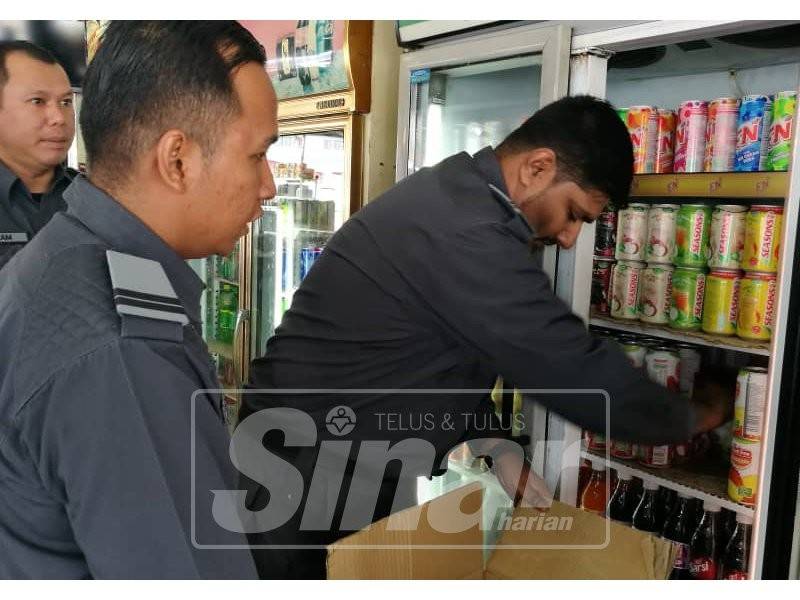 Anggota penguat kuasa merampas minuman tin yang tidak dipamerkan harga.