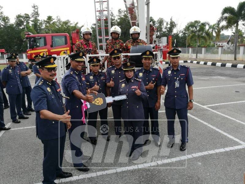 Nor Hisham (dua kiri) membuat penyerahan kunci kenderaan skylift kepada Balai Bomba Indera Mahkota.