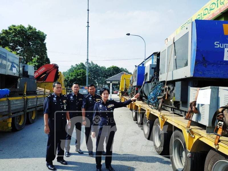 Nurulhuda (kanan) bersama pegawainya menunjukkan mesin dan lori yang dirampas dalam serbuan berkenaan