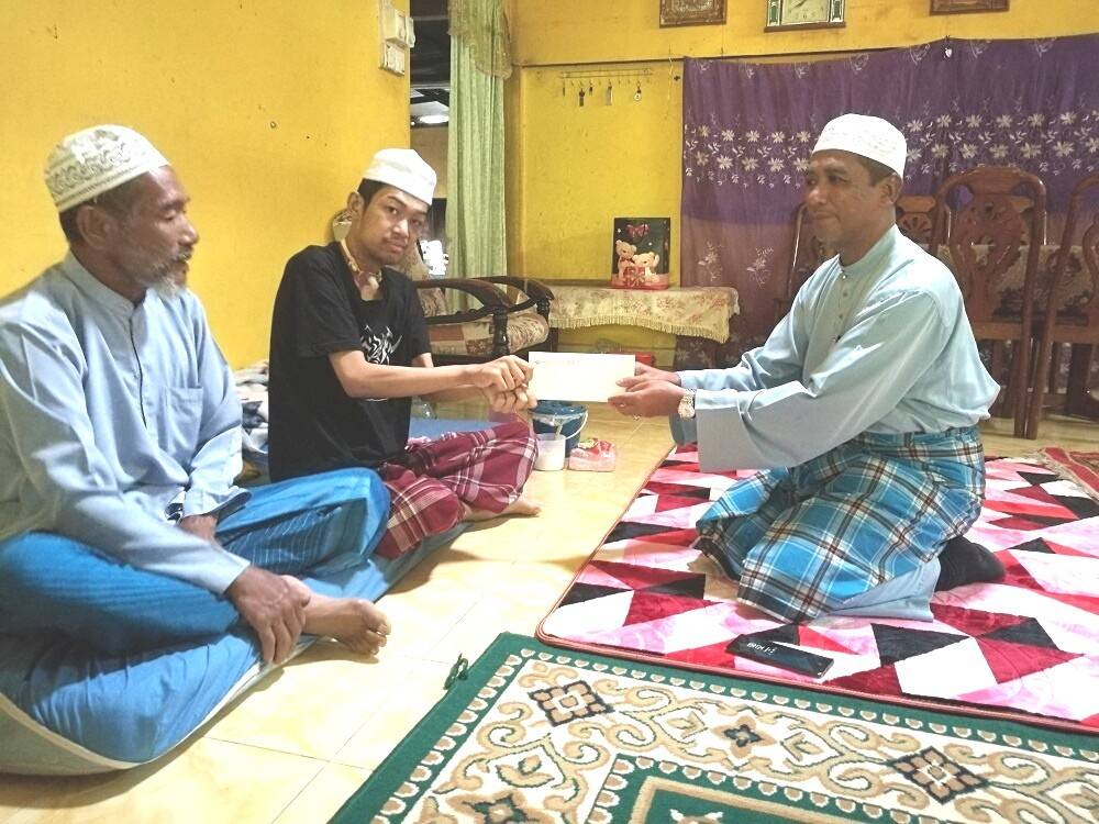 Nik Mohd Azlan menyampaikan sumbangan pada kunjungannya ke rumah Abdul Halim.