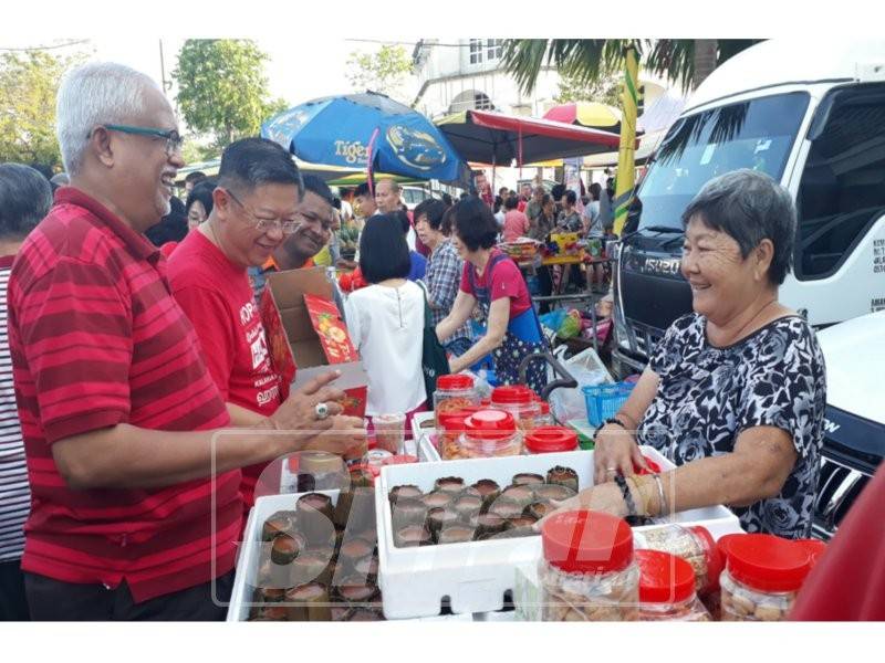 Dari kiri Mahfuz dan Kok Yew sempat bertanya kepada seorang peniaga, Ng Sok Moy,65 tentang kuih bulan yang dijual olehnya.