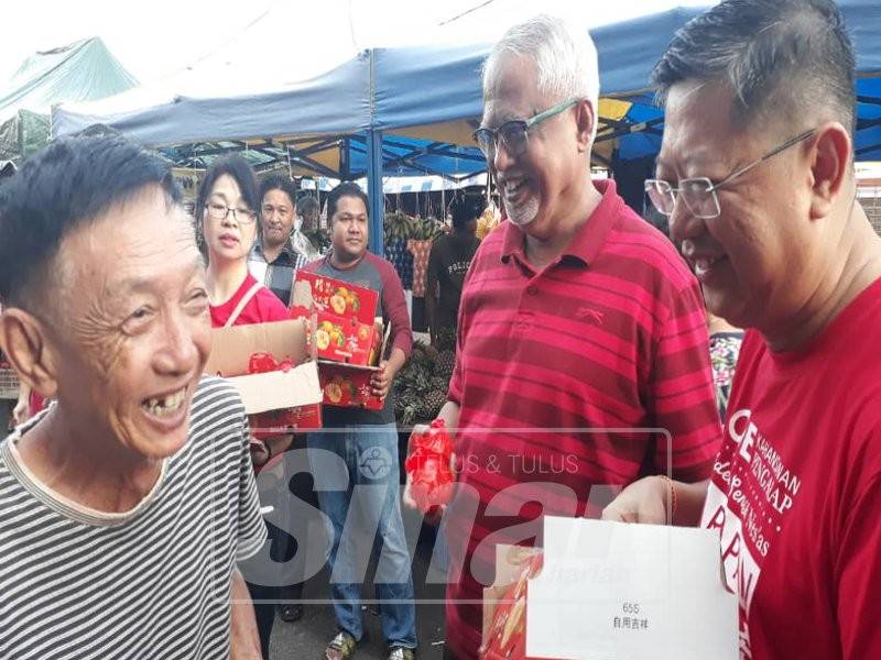 Dari kanan, Kok Yew dan Mahfuz ketika turun pada Program Serahan Buah Limau Sempena Tahun Baharu Cina di Market Cowboy, Jalan Teluk Wanjah, dekat sini, hari ini.
