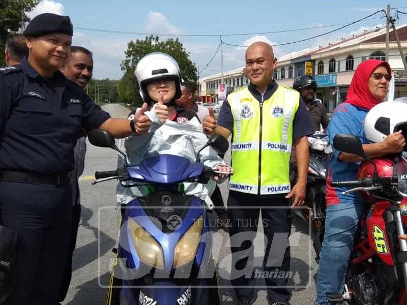 Ahmad Adnan (kiri) bersama penunggang motosikal yang menerima topi keledar percuma daripada Perkeso ketika program tersebut.