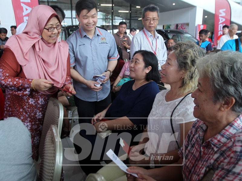 Fuziah beramah mesra bersama sebahagian penerima pada program serahan baucer kepada golongan kurang berkemampuan di TMG Bandar Putra/Tanjung Lumpur di sini, hari ini.