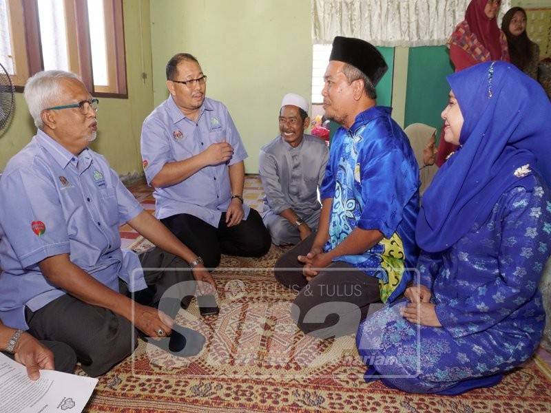 Mahfuz (kiri) bertanya khabar Abdul Hamid dan Zaiton pada majlis penyerahan cek di sini, hari ini.