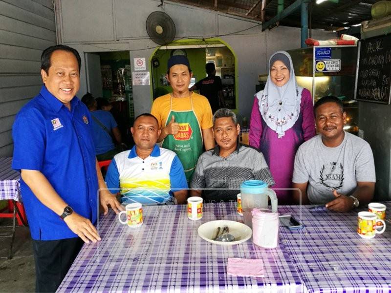 Ahmad (kiri) beramah mesra dengan pengunjung di sebuah gerai di Pontian. 