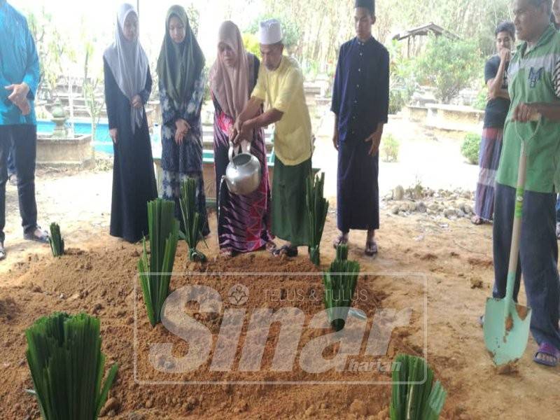 Mohd Asri Zakaria dan Zubaidah Shafie menyiram pusara ketiga-tiga anak mereka selepas selamat dikebumikan.