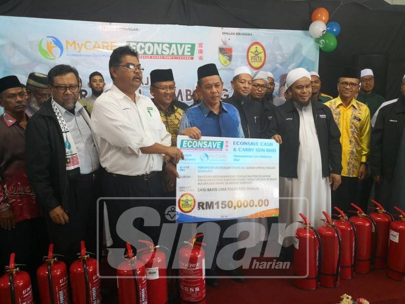 Mas Imran menyerahkan replika cek sumbangan RM150,000 kepada Aminuddin (tengah).