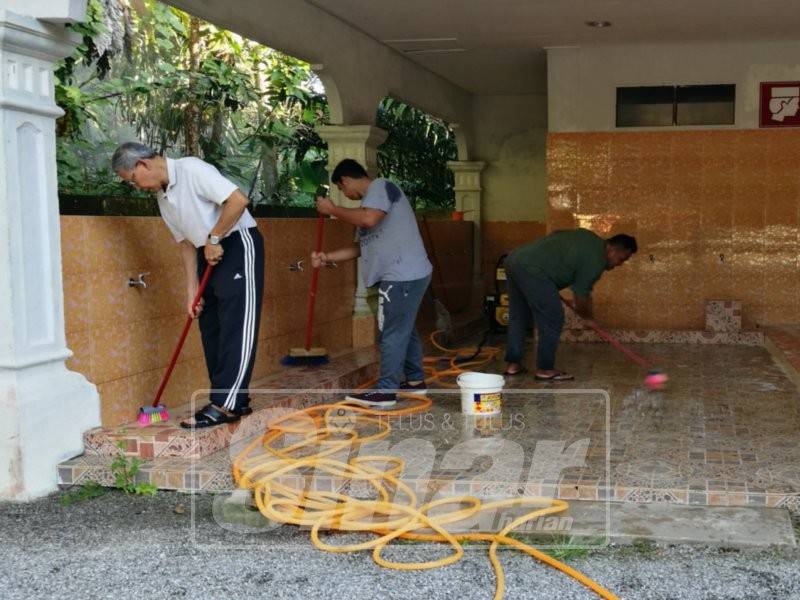 Mustapa (kiri) turut serta dalam gotong-royong berkenaan bersama skuad kebersihan dan jemaah masjid.
