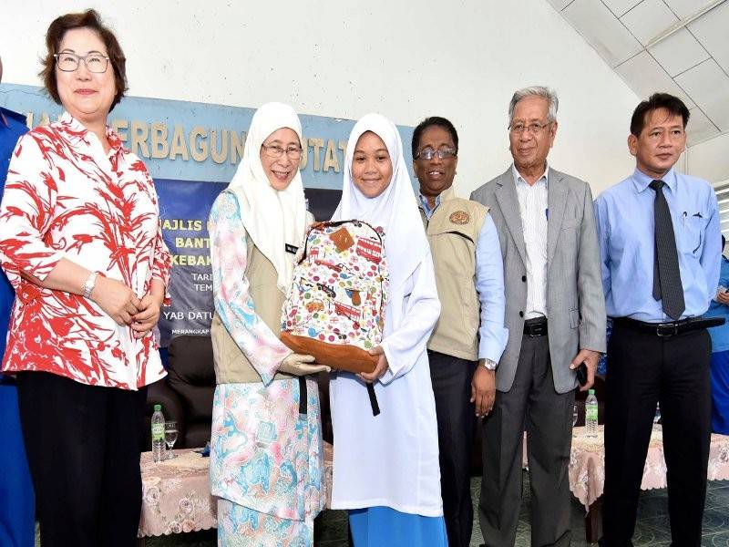 Timbalan Perdana Menteri Datuk Seri Dr Wan Azizah Wan Ismail (dua, kiri) menyampaikan bantuan beg sekolah kepada pelajar pada Majlis Penyerahan Wang Ihsan Bantuan Bencana Negara (Kebakaran) di Putatan dekat sini hari ini. - Foto Bernama