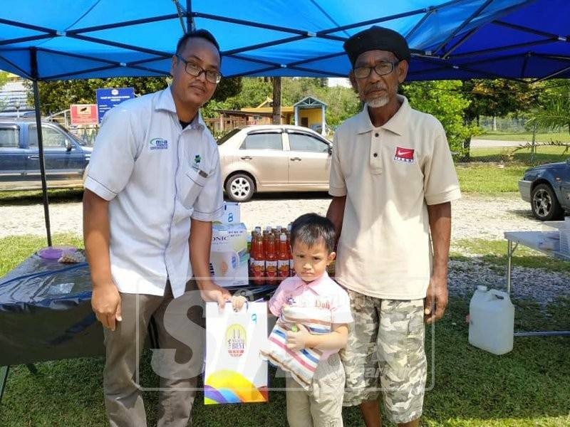 Mohd Zulkhairi (kiri) menyampaikan hadiah kepada pemenang cabutan bertuah bagi bulan Januari di Pasar Tani Masjid Bukit Perah. 