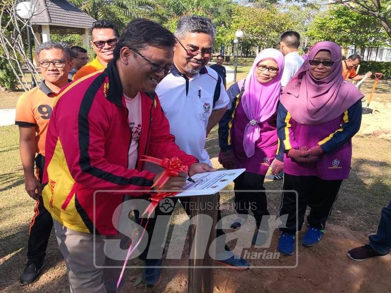 Mohamad Taufek menandatangani plak perasmian sambil diperhatikan Zazali(berbaju putih) dan Hasnah(dua dari kanan) 