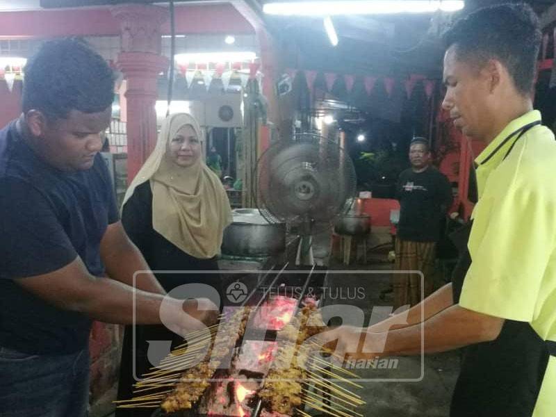 Shamsuria melihat dua pekerjanya membakar sate di kedainya di pekan Jabi malam tadi.