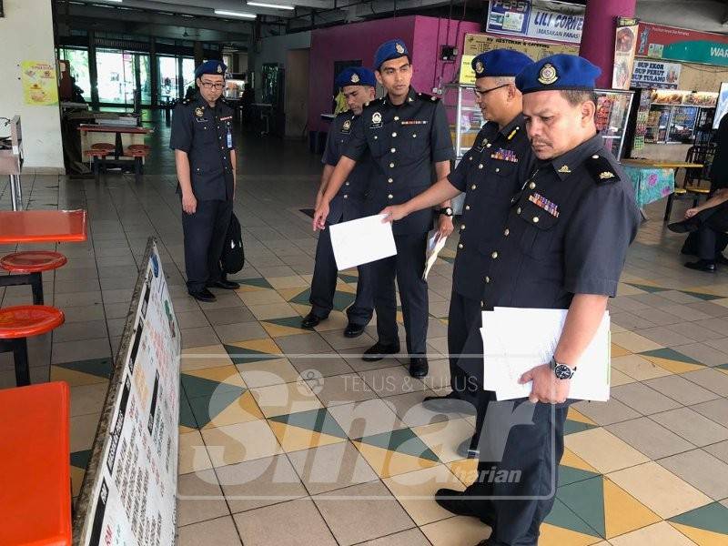 Khalid (dua, kanan) menunjukkan papan tanda harga yang diturunkan selepas operasi hari ini.