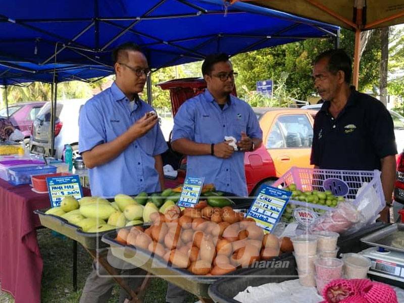 Mohd Zulkhairi (kiri) sewaktu turun padang ke Pasar Tani Masjid Bukit Perah meninjau operasi jualan.