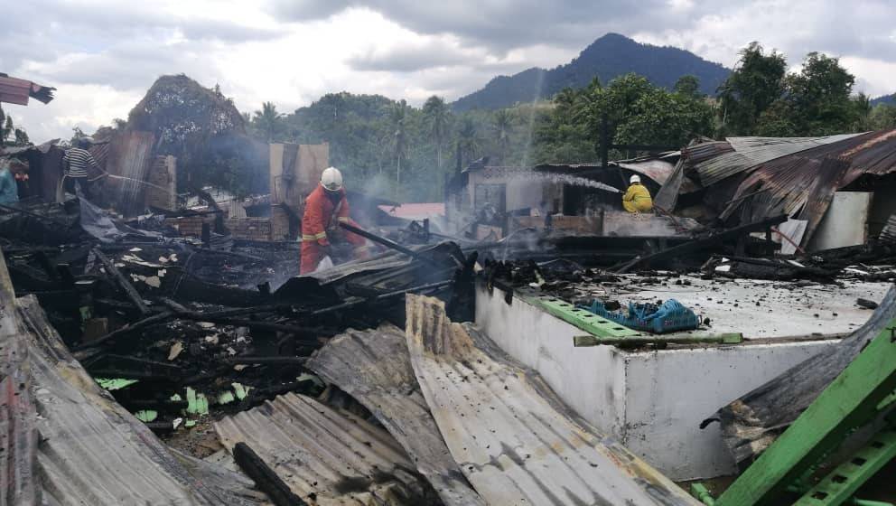 Anggota bomba bertungkus lumus memadam kebakaran dua rumah dan tiga premis di Jalan Hospital, Jeli, hari ini.