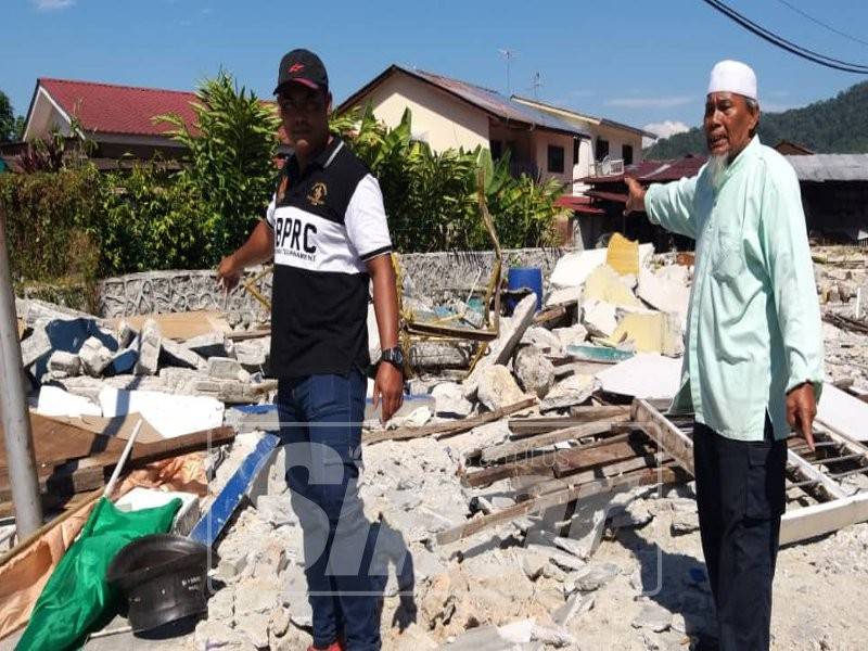 Afzainizam (kiri) bersama bapanya, Abdullah Saad menunjukkan tapak gerai mereka dirobohkan, semalam.