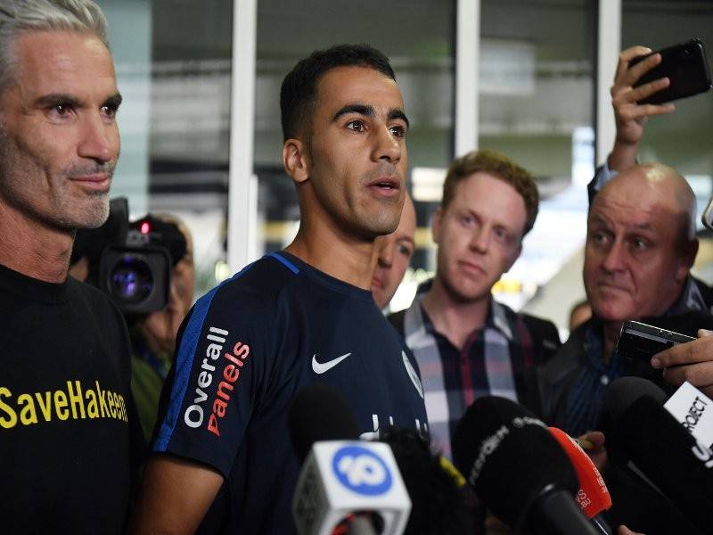 Hakeem al-Araibi (tengah) ditemani bekas kapten pasukan kebangsaan Australia Craig Foster (kiri) ketika tiba di Lapangan Terbang Melbourne hari ini. - Foto AFP
