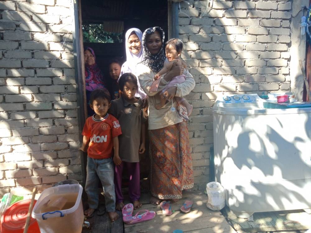 
Suzani bersama lima anak dan ibunya di hadapan rumah mereka.