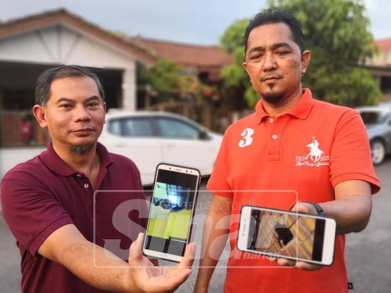 Mohamad Muazam (kanan) bersama penduduk menunjukkan gambar bumbung rumah penduduk berlubang disebabkan batu kuari 'terbang'.