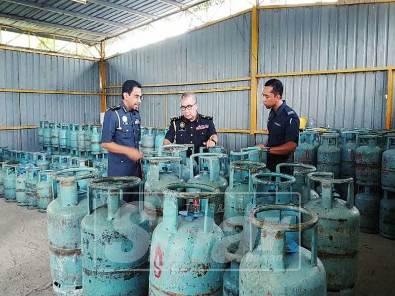 Rosli (tengah) memeriksa tong gas LPG yang disita KPDNHEP