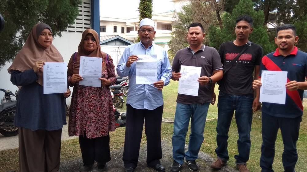 Azman Shapawi (tiga، kanan) bersama beberapa mangsa yang lain menunjukkan laporan polis yang dibuat sebelum ini berkaitan penipuan individu terbabit. 